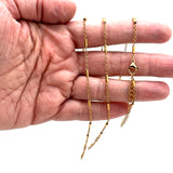 golden satellite tube chain bracelet with lobster claw clasp and extender on a hand against white background. 