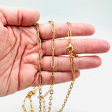 golden medium link paperclip chain necklace with lobster claw clasp and displayed on a hand with white background. 