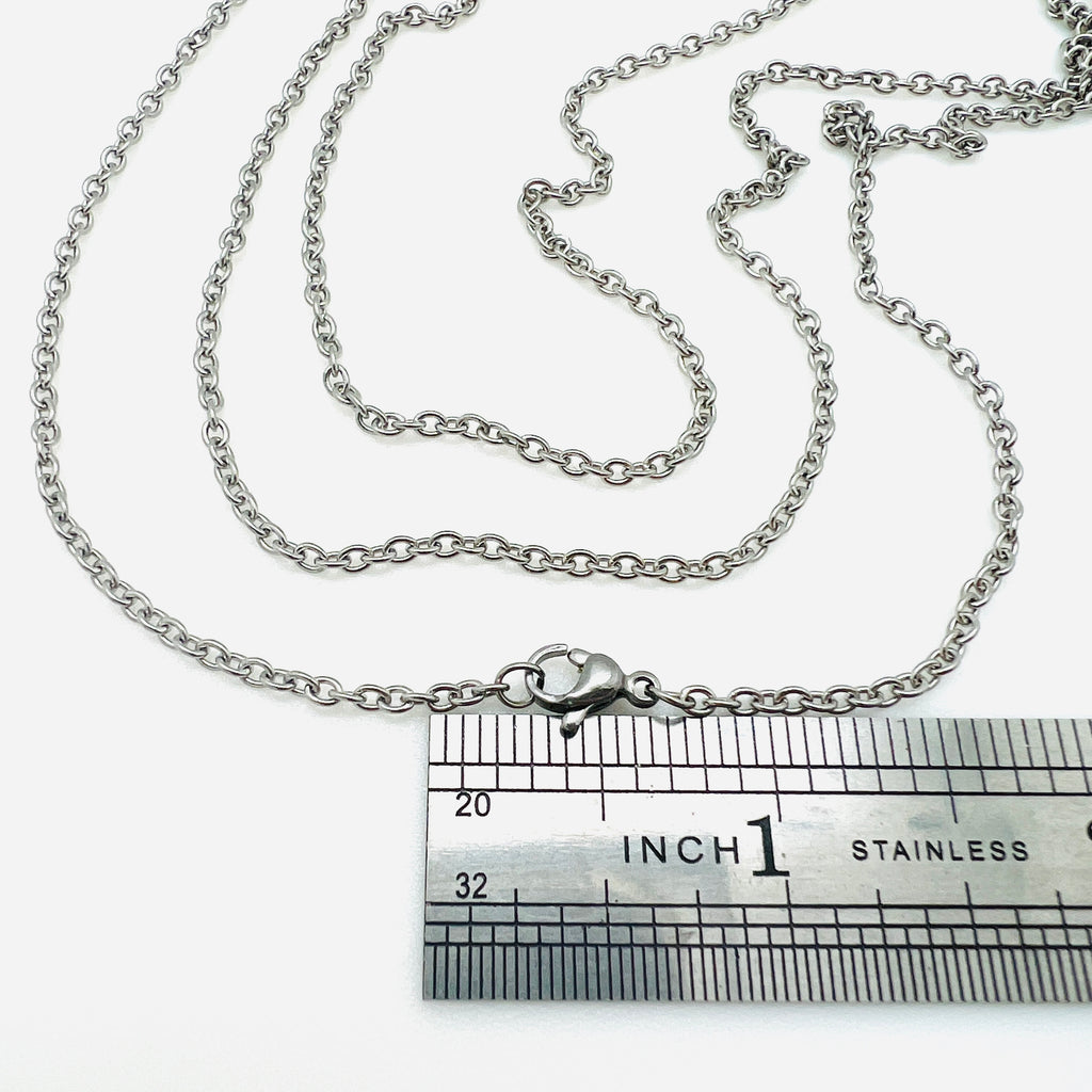 silver tone cable chain necklace with lobster claw clasp displayed above a ruler over white background. 