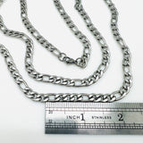stainless steel Figaro chain necklace with lobster claw clasp above a silver imperial ruler on a white background. 