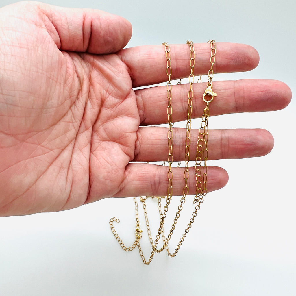 small golden paperclip chain necklace with lobster claw clasp and extender draped over hand over white background. 