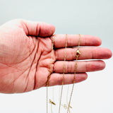 golden tiny paperclip necklace with lobster claw clasp on a hand against white background.