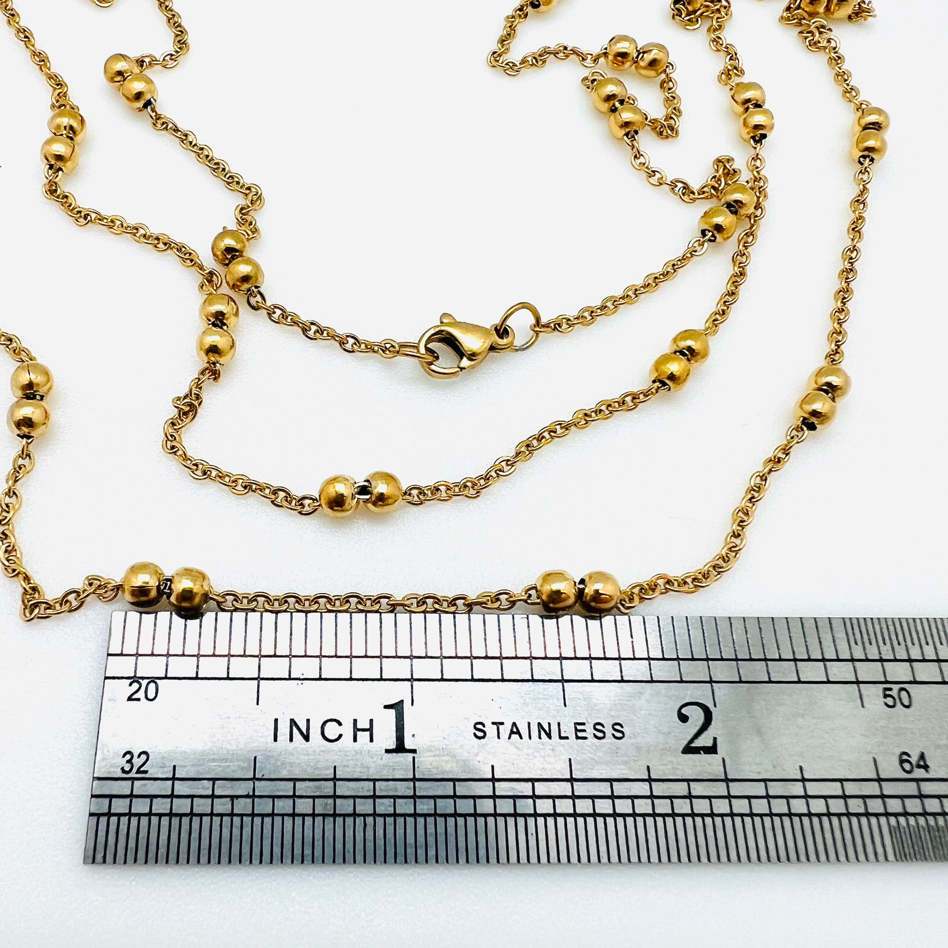 golden cable link double satellite chain necklace with lobster claw clasp above a silver ruler with a white background. 
