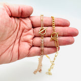 golden mixed chain necklaces one with cob leaf and paperclip links and the other with curb chain and paperclip links displayed on hand on white background. 