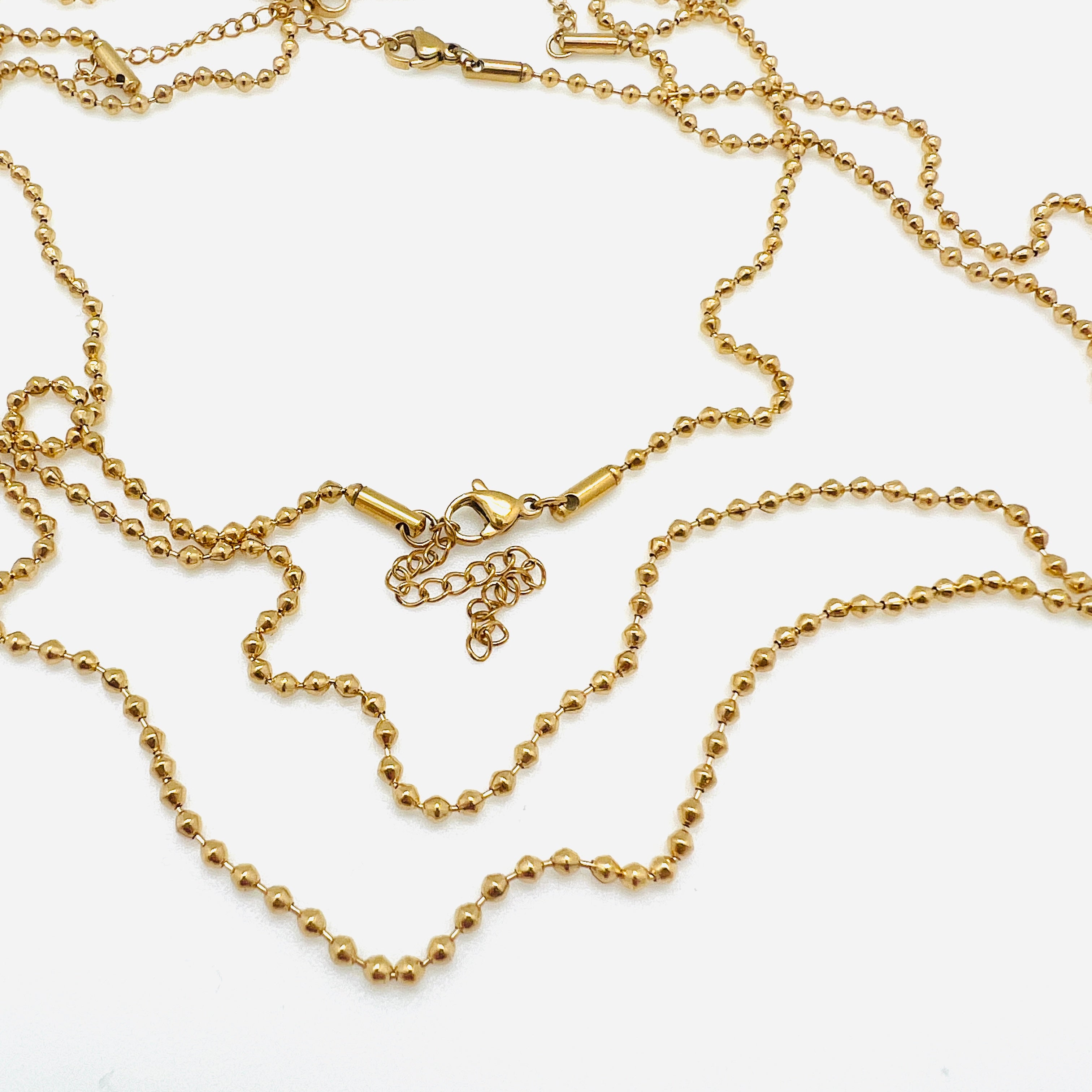 golden ball chain necklace with a lobster claw clasp and extender on a white background. 