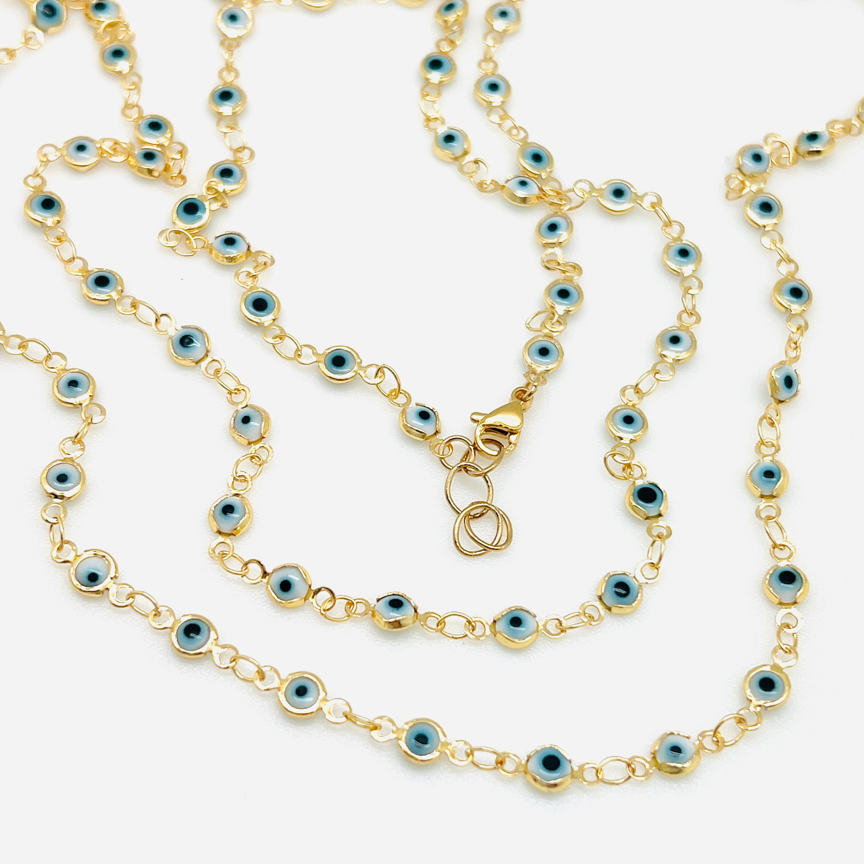 golden white and pale blue Evil Eye link chain necklace with lobster claw clasp over white background. 