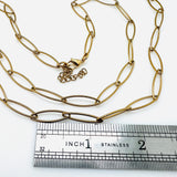 golden marquise paperclip chain necklace with lobster claw clasp and extender chain above stainless steel imperial ruler on white background. 