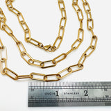 golden paperclip link chain necklace with lobster claw clasp above a silver imperial ruler with a white background. 