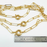 3 golden paperclip chain necklaces with large spring ring clasp above stainless steel imperial ruler on white background. 