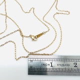 golden tiny paperclip necklace with lobster claw clasp above stainless steel imperial ruler  on white background.