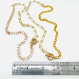 golden mixed chain necklaces one with cob leaf and paperclip links and the other with curb chain and paperclip links above stainless steel imperial ruler on white background. 