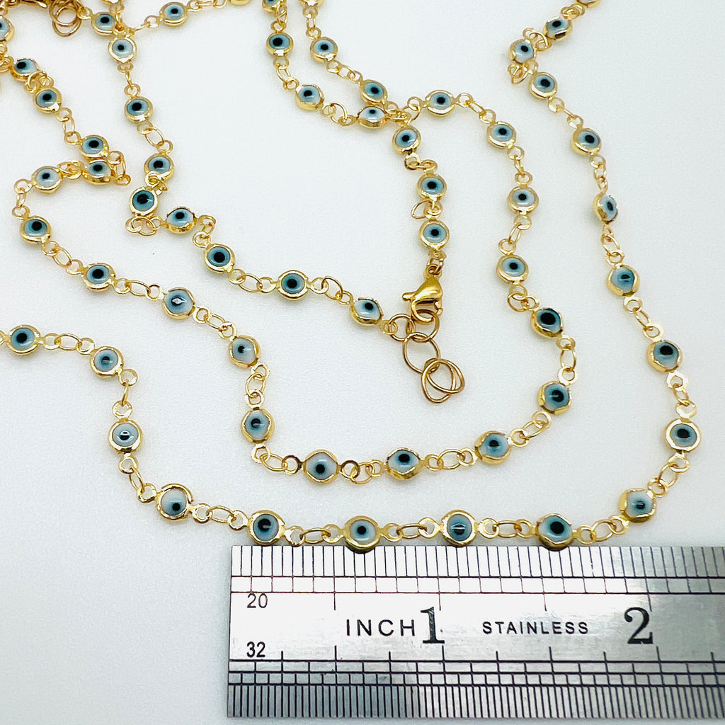 golden white and pale blue Evil Eye link chain necklace with lobster claw clasp  displayed over a ruler over white background. 