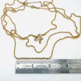 golden ball chain necklace with a lobster claw clasp and extender shown near a silver imperial ruler  on a white background. 