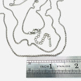 stainless steel Rolo chain with lobster claw clasp and extender chain above stainless steel imperial ruler on white background. 