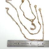 golden satellite tube chain bracelet with lobster claw clasp and extender above a stainless steel imperial ruler against on white background. 