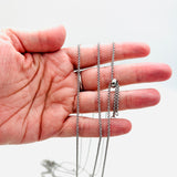 stainless steel, adjustable, rolo chain with slider stopper bead displayed on a hand with a white background. 