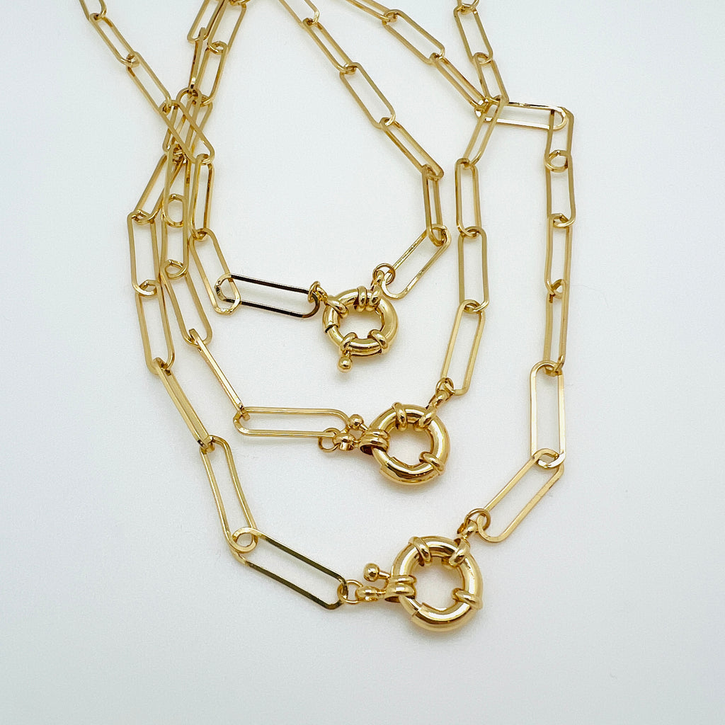 three golden paperclip link bracelets with large spring ring clasp on white background. 