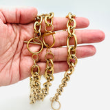 two golden Rolo chain necklaces with toggle clasp on a hand with a white background. 