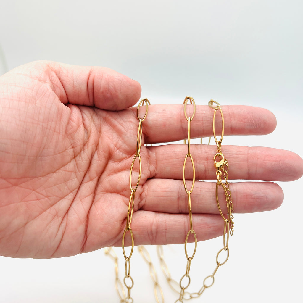 golden marquise paperclip chain necklace with lobster claw clasp and extender chain draped over a hand against white background. 