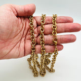 golden large Rolo chain necklace with lobster claw clasp on a hand on white background. 