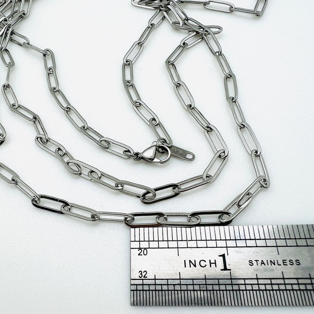 silver tone medium link paperclip chain necklace with lobster claw clasp above stainless steel ruler on white background. 
