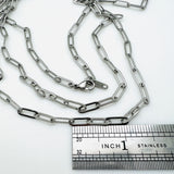 stainless steel medium link paperclip chain necklace with lobster claw clasp above stainless steel imperial ruler  on white background. 