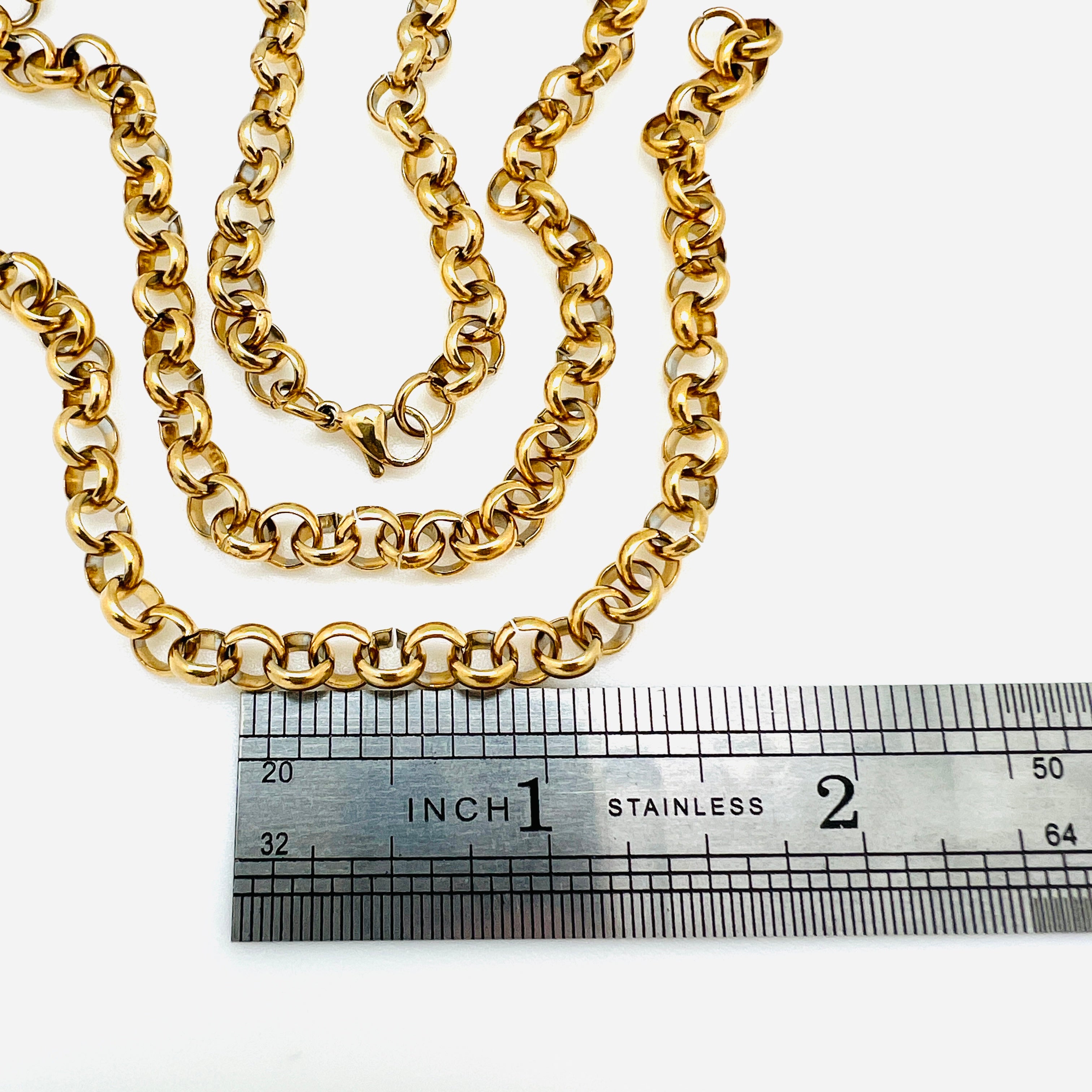 three golden rolo chain bracelets with lobster claw clasps displayed above ruler with white background. 