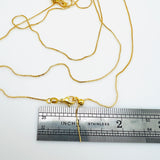 gold plated brass, adjustable box chain with lobster claw clasp shown with a silver imperial ruler on a white background.