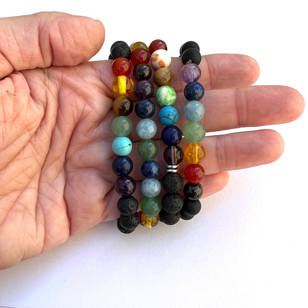 four different versions of stretch chakra bracelets displayed on a handover white background. 