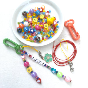 Beaded Backpack clip kit. Add your own name like this one that says IZZY. Photos show two clips, an assortment of colorful beads, charms and connectors. 
