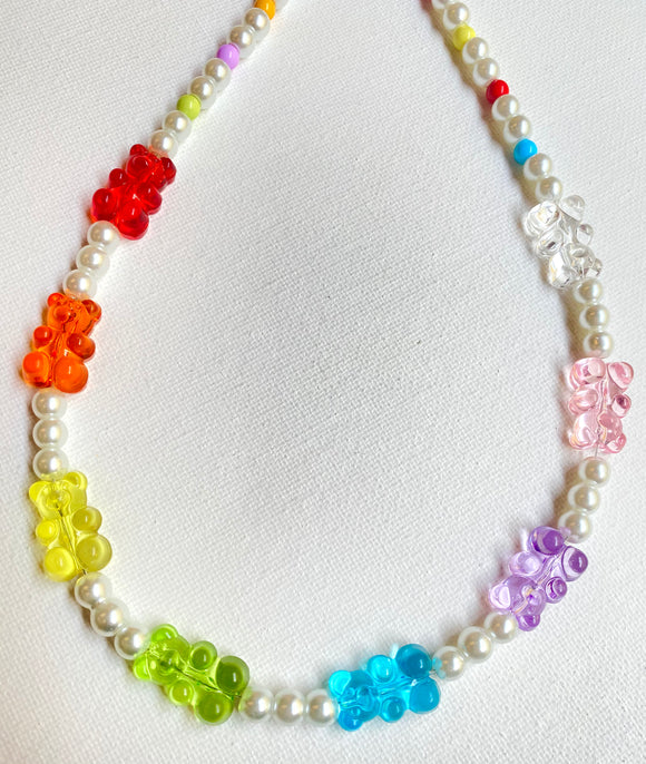 A necklace with 8 resin gummy bear beads in rainbow colors, on a strand of white glass faux pearl beads 
