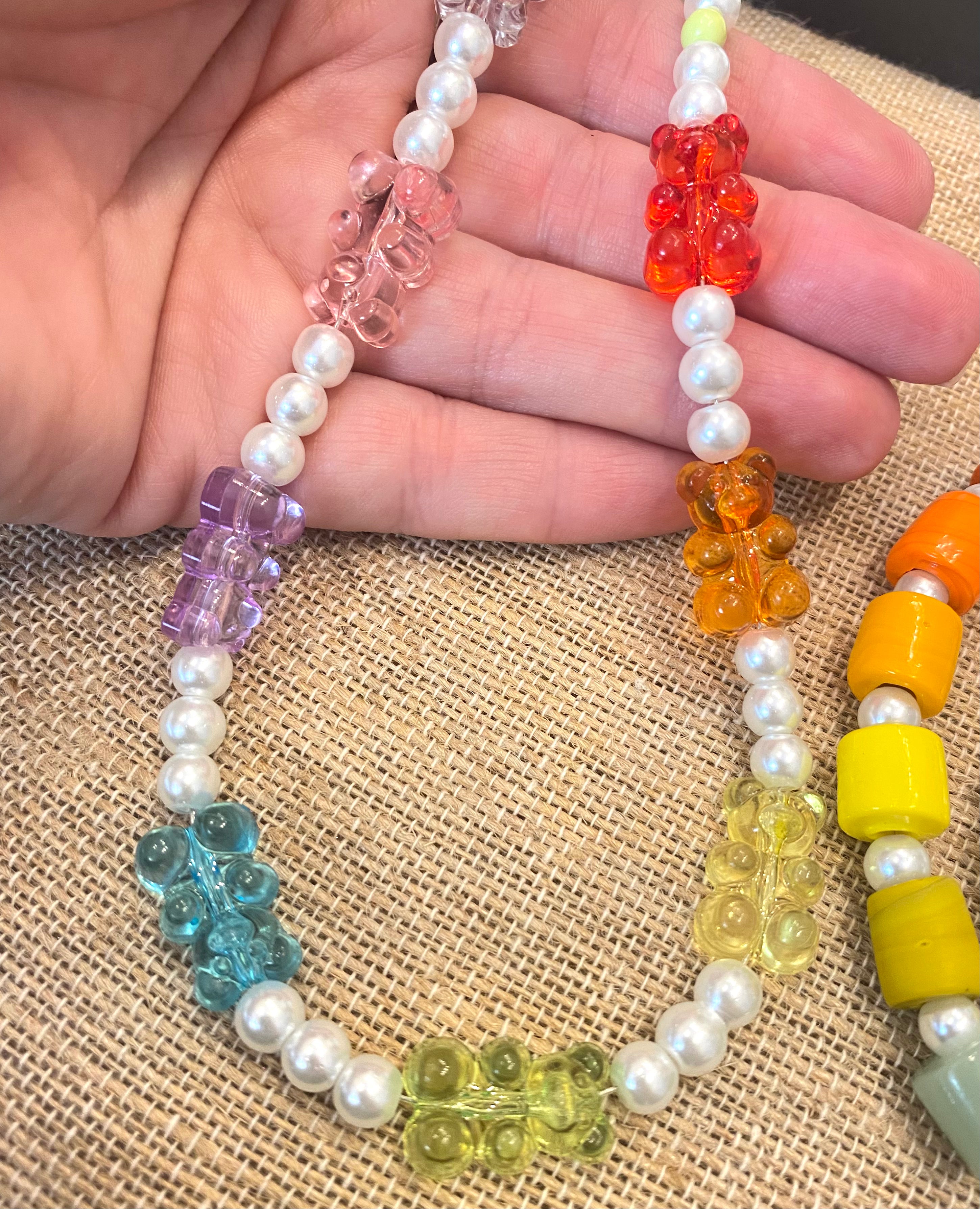 A wimans hand holding a necklave made with our gummy bear glass pearl gummy bear kit. 