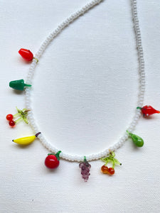Photo is multi-color glass fruit charms strung on white seed beads on a white background