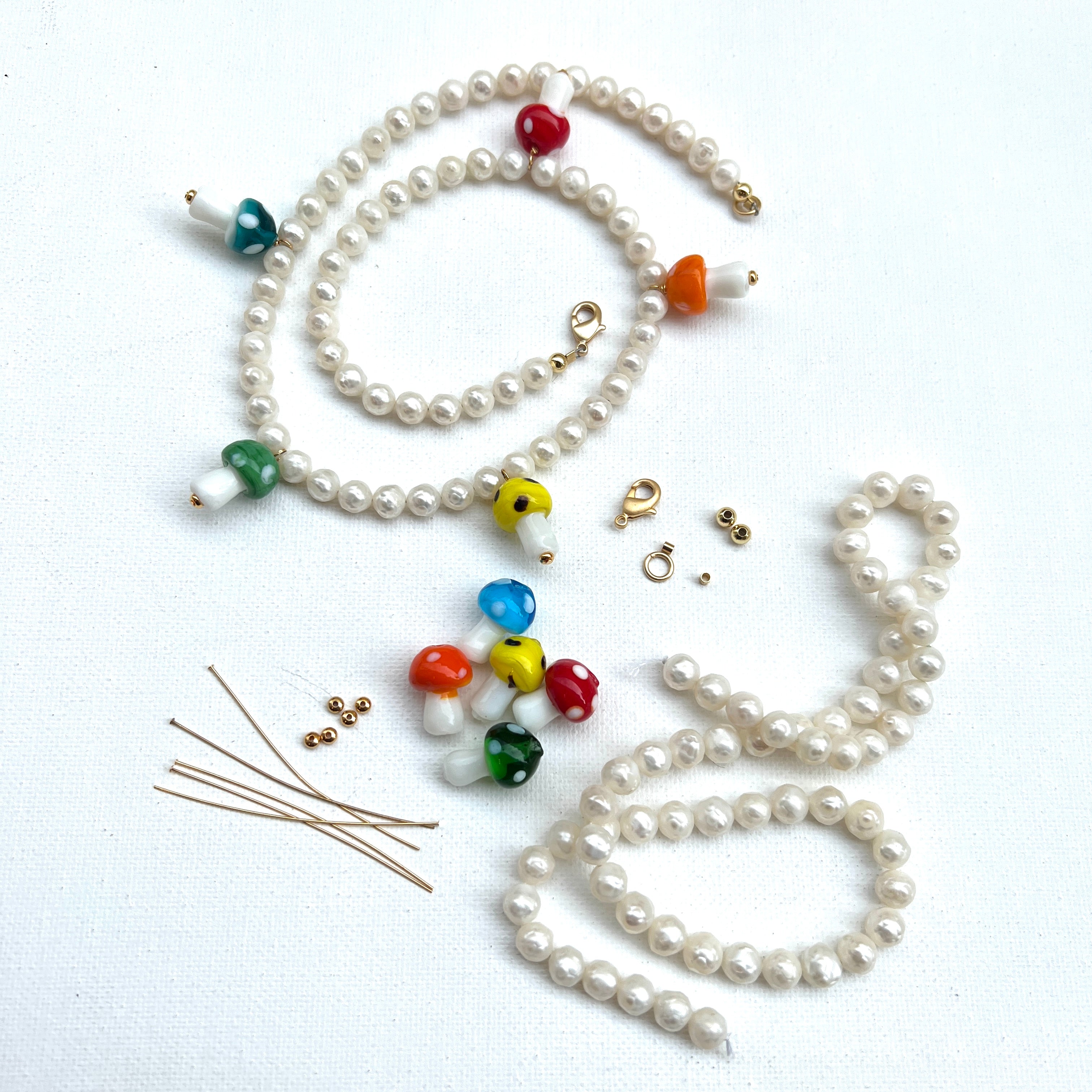 multi-color glass mushrooms and white freshwater pearls with gold findings on a white background