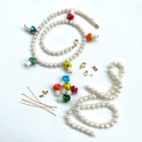 multi-color glass mushrooms and white freshwater pearls with gold findings on a white background