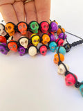 multiple multi-colored stone skull bracelets in a hand for scale