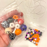 picture shows Halloween colored beads in plastic bags as a representation of what comes in the beading kit