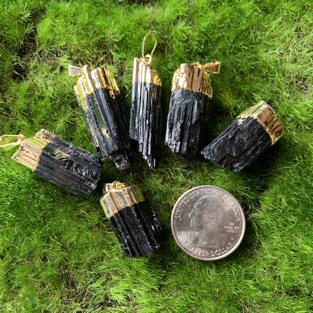 raw black tourmaline pendant with gold electroplated cap on green background with US quarter for scale