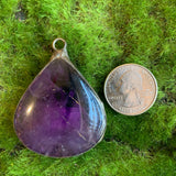amethyst pendant on green background with US quarter for scale