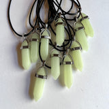 glow in the dark pendants on black cord with a white background
