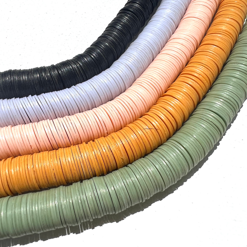 black, blue-grey, pale pink, yellow orange, and sage green vinyl disks on a white background