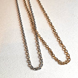 stainless steel and golden flat cable chain necklaces displayed together on white background. 