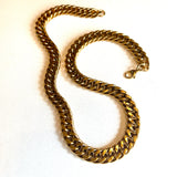 golden large Cuban link chain necklace with lobster claw clasp on white background. 