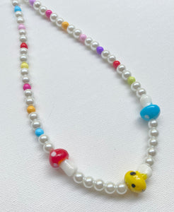 Photo is of multi-color glass mushroom and glass pearl necklace on a white background